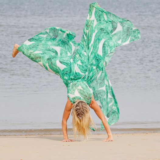 woman in green and white jumpsuit doing a cartwheel